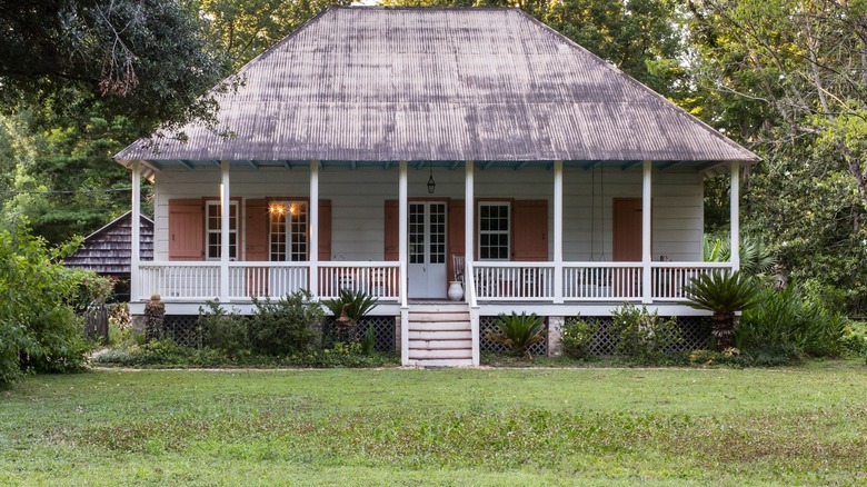 Historical Acadian house with spacious front porch, lush trees in the background, Valsin Broussard House, Louisiana