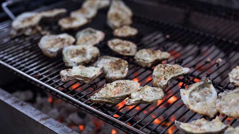 Charbroiled oysters cooking on an open grill