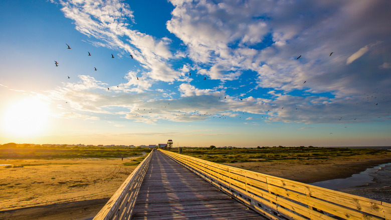 The sun setting above a boardwalk and beach in Grand Isle State Park, Louisiana
