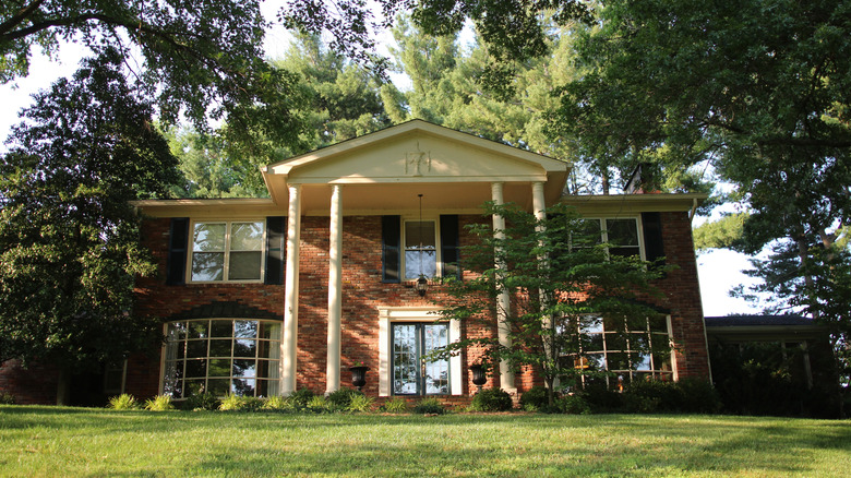 A beautiful brick Colonial home with a large grass lawn and trees in Anchorage, Kentucky