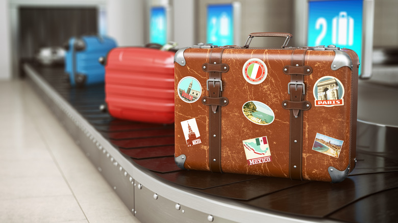 Old vintage suitcase with stickers on top of carousel