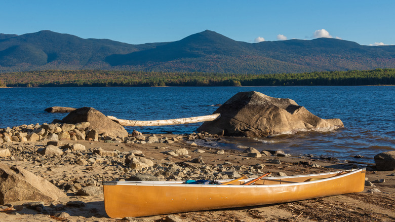A beached canoe at Flagstaff Lake with mountains in the distance