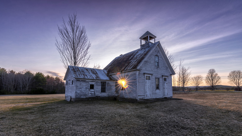 Small schoolhouse in Harrison, Maine with sun peeking through a window.