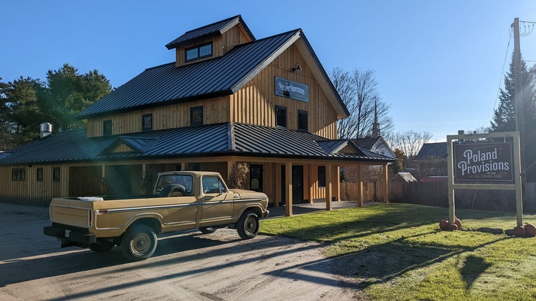 blue sky over wooden building on green grass with black sign and white letters