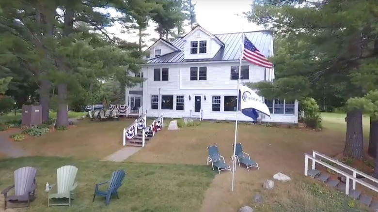 white building next to green trees under blue sky with american flag in front