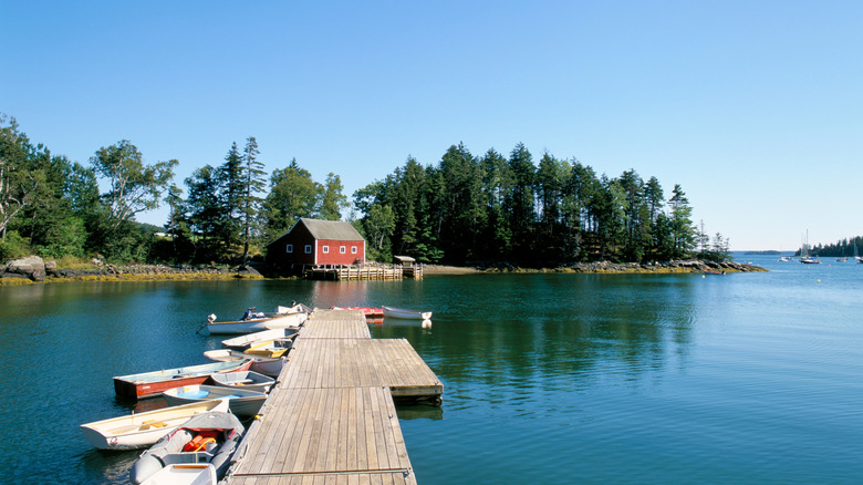 A jetty with boats, trees and a red house on the harbor in Brooksvile