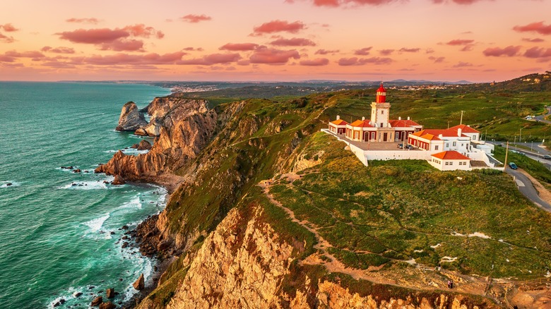 Lighthouse on cliffs at sunset