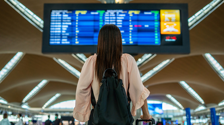 Woman looking at a flight schedule board in an airport
