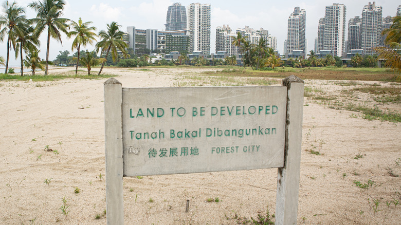 A sign on a Forest City beach saying "Land to be developed" in Malaysia