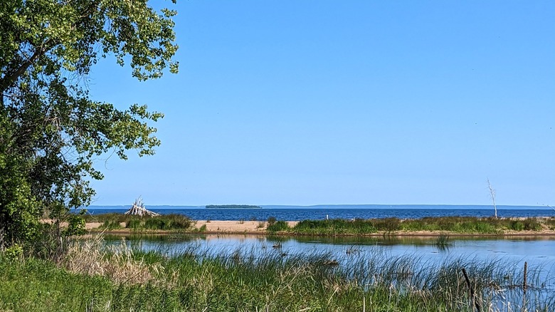 Red Arrow Park Beach with small sand dunes, grass, and Lake Michigan in front, while the Door County Peninsula is on the horizon