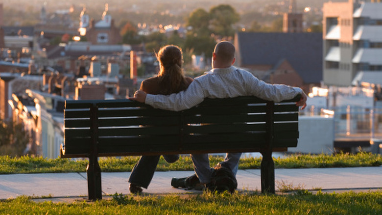 Couple on a black bench overlooking buildings of Baltimore