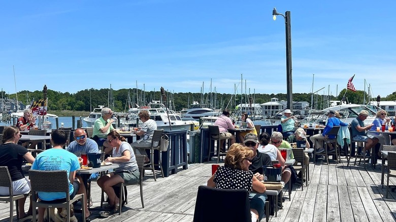 People eating on dock surrounded by boats