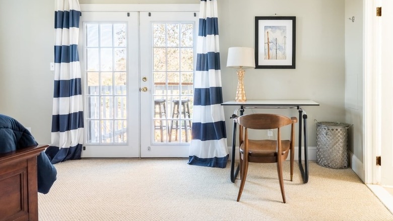 Desk with wooden chair facing balcony doors in bright room