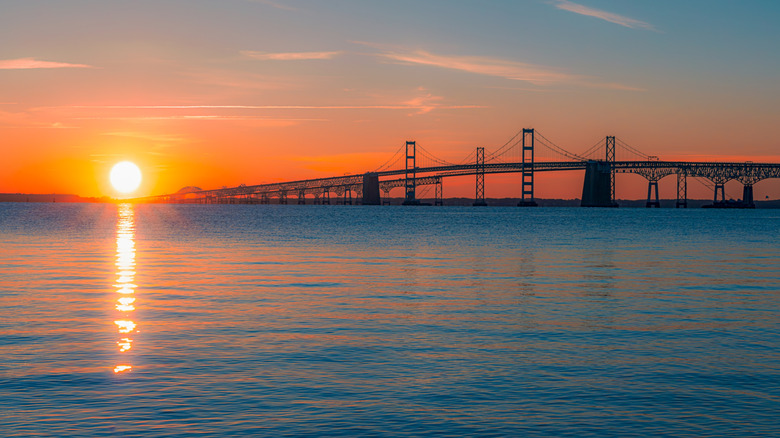 The Chesapeake Bay Bridge sits over the bay, with the sun setting to the left