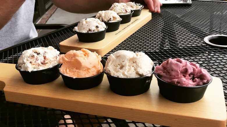 Two wooden paddles, each with four ice cream cups of different flavors