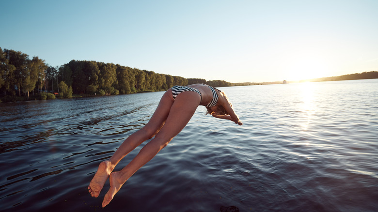 Swimmer diving into a lake surrounded by forest