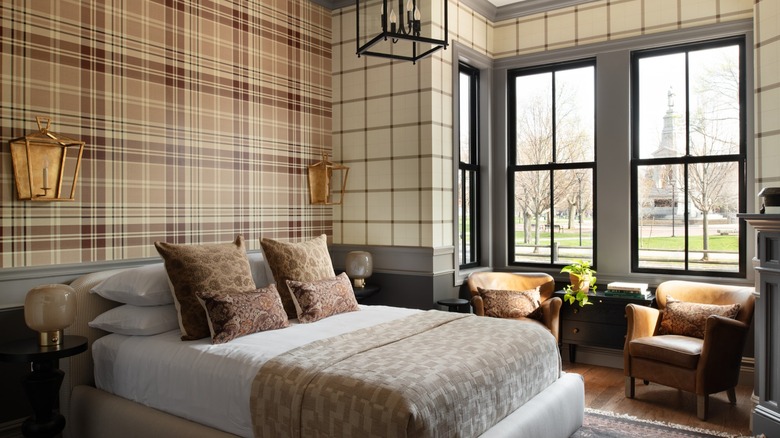 Hotel bed with plaid walls and windows overlooking square