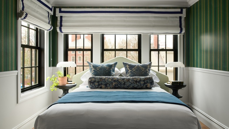 Bed with decorative pillows surrounded by windows and green walls in Cambridge Common House