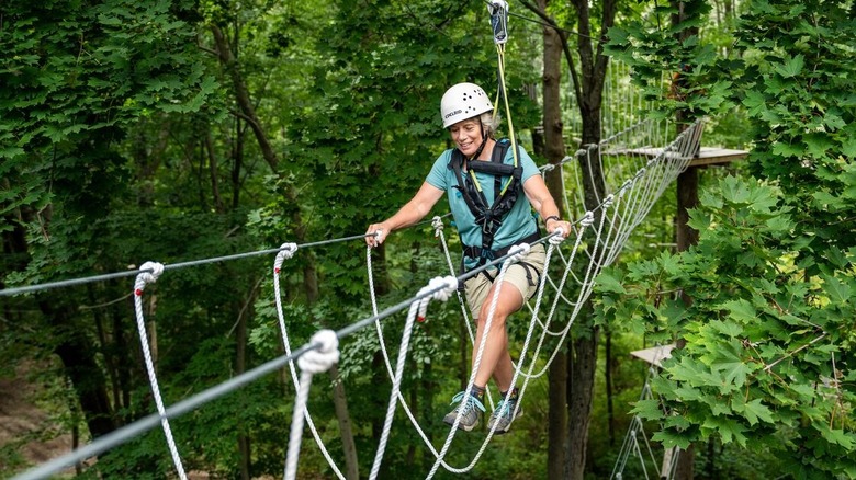 A woman traverses a rope bridge on the course at Miraval Berkshires