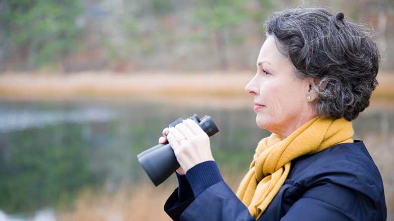 A woman with a yellow scarf holding binoculars