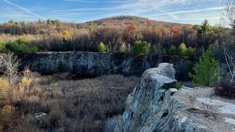 A wooded hill rises above stone walls at the Mineral Hills quarry in rural Massachusetts