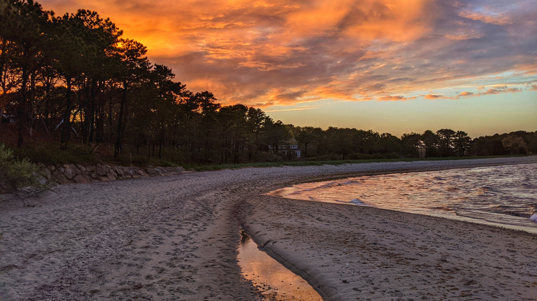 Sunset over water and beach with sand on Cape Cod near Cotuit