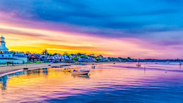 Sunset over Provincetown Harbor in the Outer Cape, vibrant purples, pinks, and golds in the sky over the water and boats