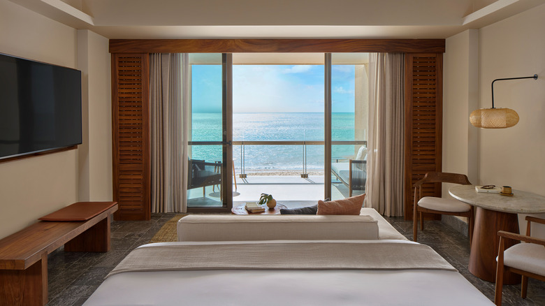 A hotel room appointed in warm wood, natural stone, and earth tones with sea views at the Park Hyatt Riviera Maya