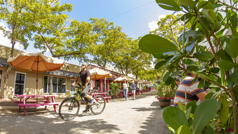 Bikers pass shops and cafes on the streets of Coconut Grove in Miami, FL