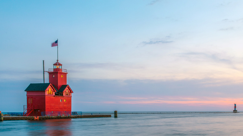 The sun setting on the "Big Red" Lighthouse on Holland State Park's Pier in Michigan
