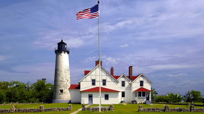 Landscape view of historic Point Iroquois Lighthouse with a large American flag flying in front