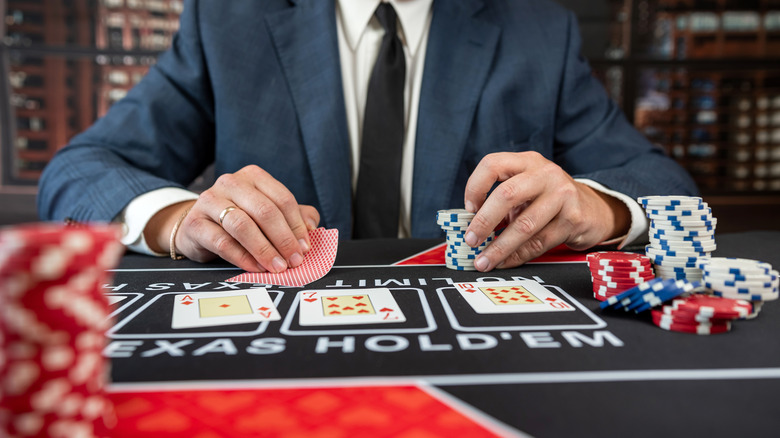 Someone wearing a suit and shuffling cards at a casino table