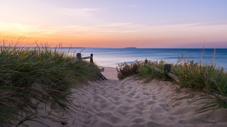 Sandy path leading to Au Train Beach with a colorful sky at sunset