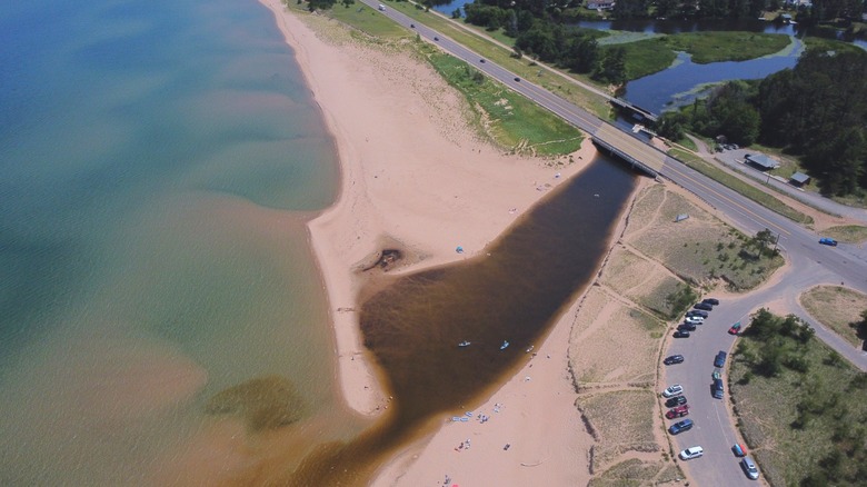 The Au Train River emptying into Lake Superior at a sandy beach, near a road and parking lot
