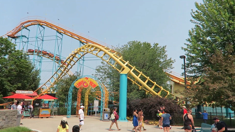 People walking past Michigan Adventure's Corkscrew roller coaster.