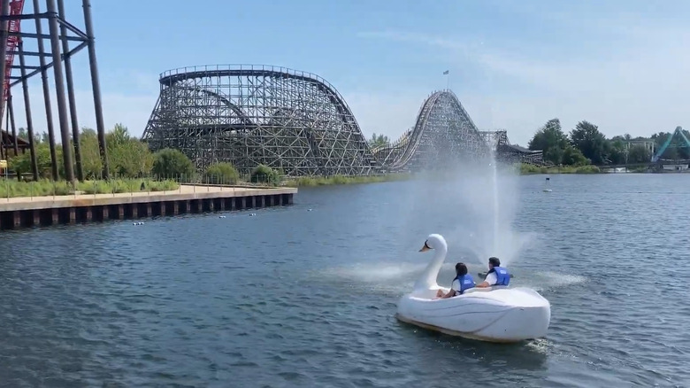 Two people on swan boat with Michigan Adventure coaster in background.