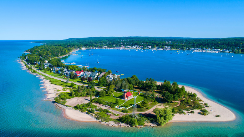 Aerial view of trees and beach surrounding lighthouse on Little Traverse Bay with Harbor Springs across the water