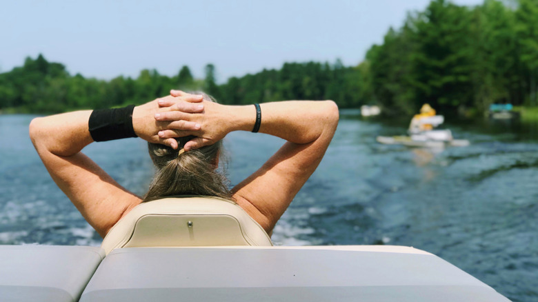Senior woman relaxing on a pontoon boat in a Michigan lake, leaning back with hands clasped behind her head