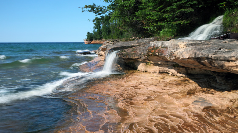colorful rock cliffs along Lake Superior with small waterfall