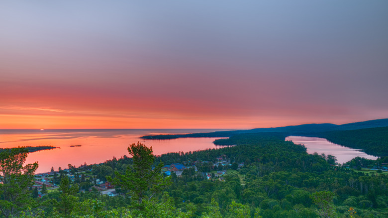 A photo from a turnoff at Brockway Mountain showing Copper Harbor at sunset with calm Lake Superior and rolling Keweenaw forest stretching to the horizon