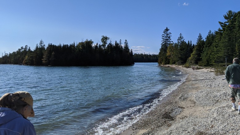 A couple walking along the stone and sand shore of Lake Huron at DeTour State Forest Campground