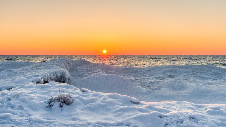 The sun setting over snow-covered dunes at Sleeping Bear Dunes National Lakeshore in winter