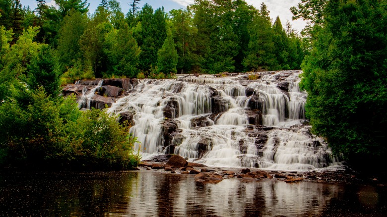 View of Bond Falls in Michigan during the day, surrounded by trees.