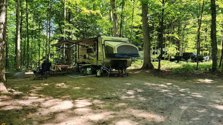 A campsite set up with RV and chairs at a fire pit at Bewabic State Park