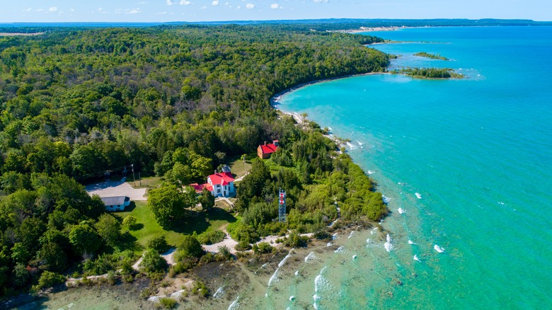 An aerial view of the Grand Traverse Lighthouse overlooking Lake Michigan on a sunny day