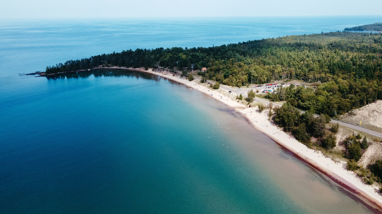An aerial view of Great Sand Bay, showing a sand beach, blue waters, and trees in the background