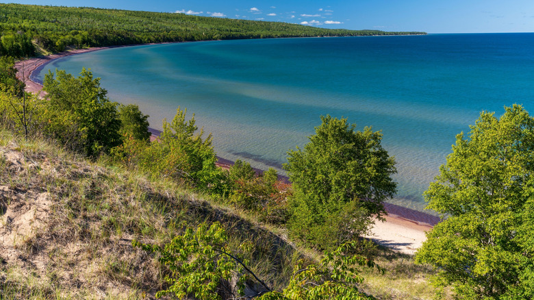 An aerial view of Mohawk, Michigan and Lake Superior, showing trees and clear water.