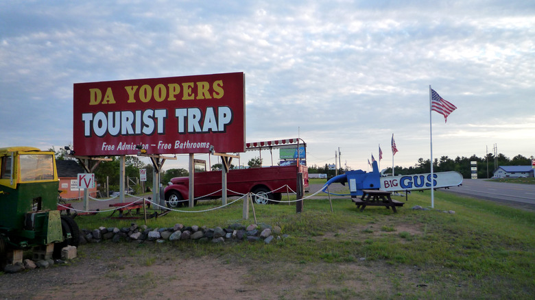 A sign reading "Da Yoopers Tourist Trap" with various vehicles and items around it