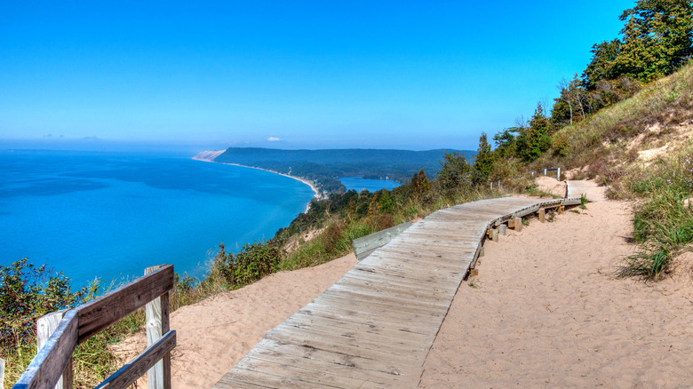 A wooden walkway on a sand dune at Sleeping Bear Dunes National Lakeshore, with scenic views of Lake Michigan in the background