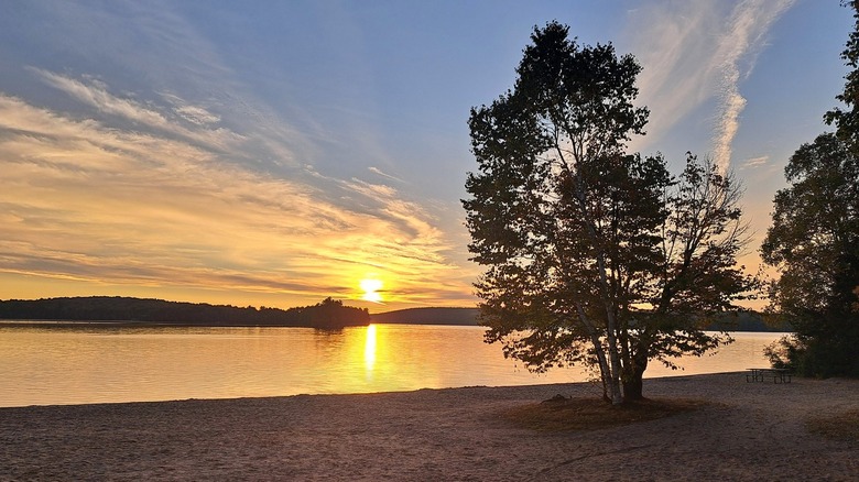 A sandy beach with a colorful sunrise at Eagle Lake in Mikisew Provincial Park, Ontario